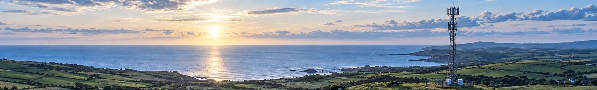 Cell tower above a rural coastline at sunrise